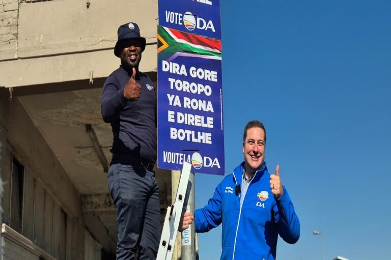 Democratic Alliance (DA) Leader Geordin Hill-Lewis and the party's Federal Leader Solly Msimanga hang up election poster.