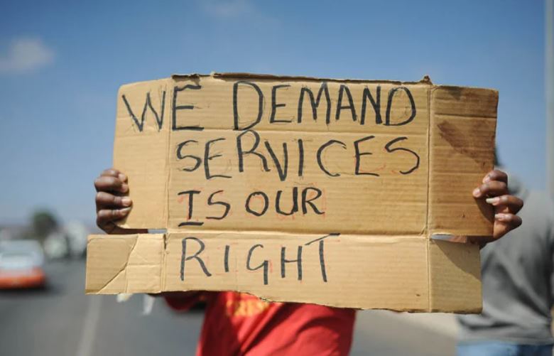 FILE | A person holding a placard demanding services during a protest.